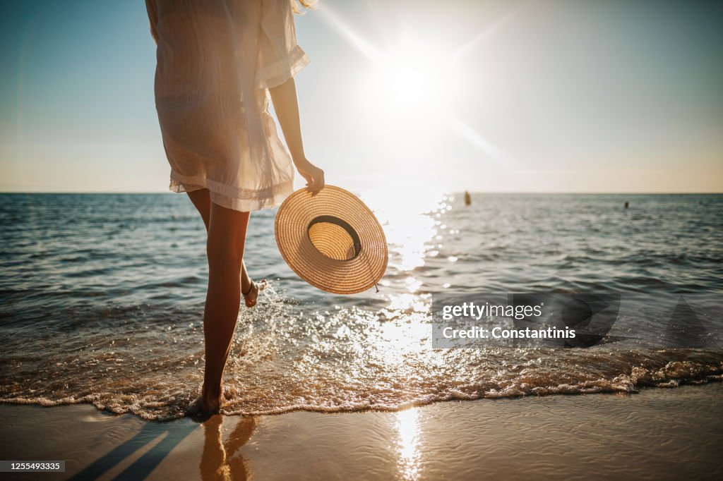 De benen die van de vrouw water op het strand bespatten