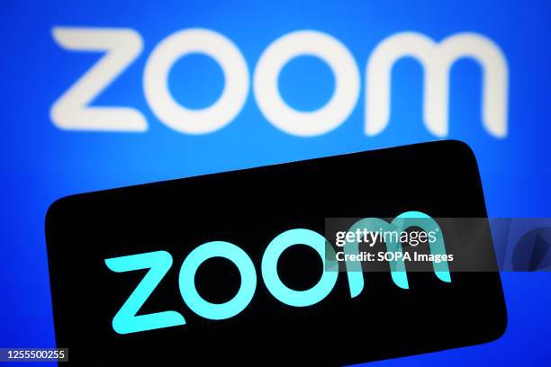 In this photo illustration, Zoom Video Communications logo is seen on a smartphone and on a pc screen.