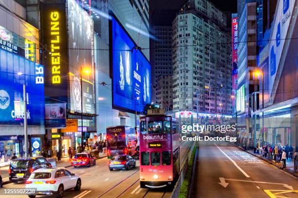 local tram, bus, taxi, and car on the street of causeway bay at night with background of light from advertising signs of sogo shopping centre, causeway bay, hong kong - sogo stock pictures, royalty-free photos & images