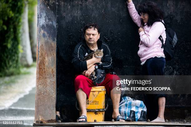 Resident holds his cat while being rescued along with a woman on a digger on May 17, 2023 in Massa Lombarda, a small village about 10 kilometers from...
