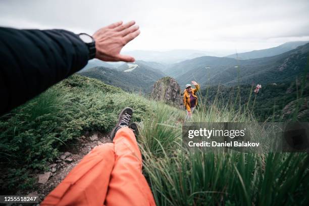 blick auf einen mann aus persönlicher perspektive mit füßen und hand in rahmen gruß an einen freund. zurück zur natur. wandertourist in den bergen mit blick auf eine schöne aussicht. genießen sie im freien an einem sommertag nach der covid-19-pandem - welcome back stock-fotos und bilder