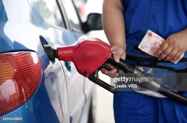 An employee wearing a face mask refuels a vehicle at a gas station of Sinopec on July 10, 2020 in Handan, Hebei Province of China.