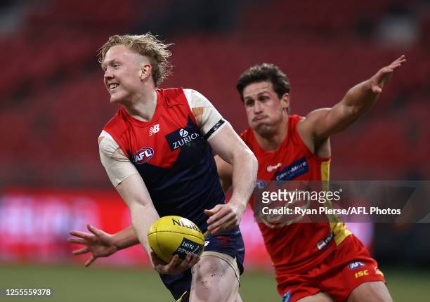 Clayton Oliver of the Demons runs clear of David Swallow of the Suns during the round 6 AFL match between the Melbourne Demons and the Gold Coast...