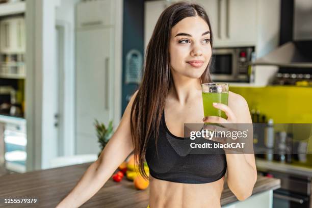 young active woman holding healthy smoothie - green drink stock pictures, royalty-free photos & images