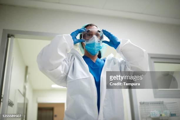 one female doctor getting dressed with ppe protective clothes. - protective workwear imagens e fotografias de stock