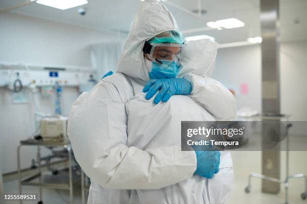 twee gezondheidswerkers knuffelen en steunen elkaar. - overall stockfoto's en -beelden