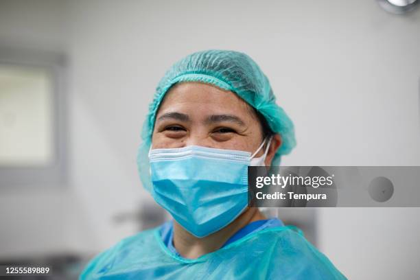 infirmière souriant fièrement à la caméra à l’hôpital. - face mask coronavirus photos et images de collection