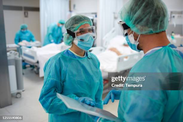 two healthcare workers talking at the uci - protective workwear imagens e fotografias de stock