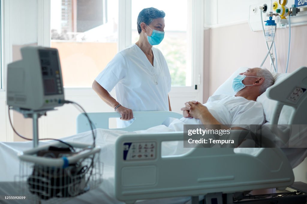 A doctor visiting a patient in a hospital ward.