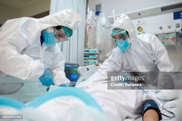 mitarbeiter im gesundheitswesen passen die geräte an einen covid-patienten an. - pandemic illness stock-fotos und bilder