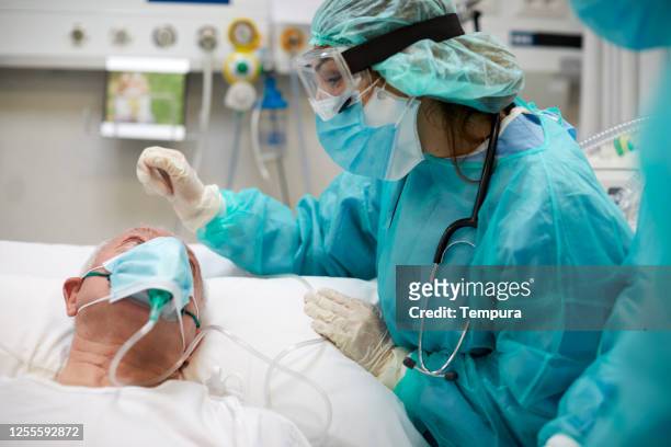 krankenschwester tröstet einen kovid endok-patienten auf der intensivstation - pandemic illness stock-fotos und bilder