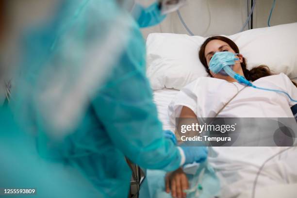 de verpleegster controleert de druppelnaald van een medevidpatiënt bij de icu - icu stockfoto's en -beelden