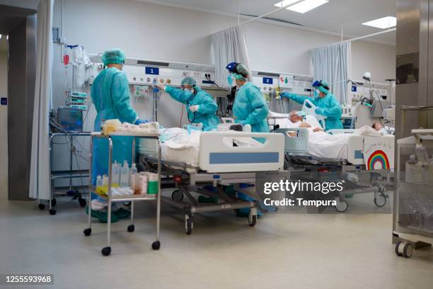 trabajadores sanitarios que ajustan el suministro de oxígeno a un paciente covid. - intubation fotografías e imágenes de stock