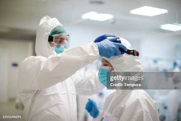 een expertisearts houdt toezicht op het correct aantrekken van beschermende kleding. - overall stockfoto's en -beelden
