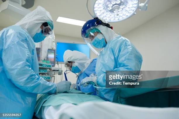 doctors suturing a wond at the operation table in covid protective workear. - surgery stock pictures, royalty-free photos & images