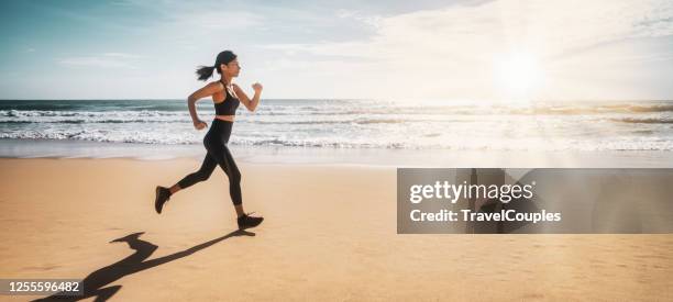 woman running on the beach at sunset. silhouette of a young girl running along the beach of the sea during an amazing sunset. - morning walk stock pictures, royalty-free photos & images