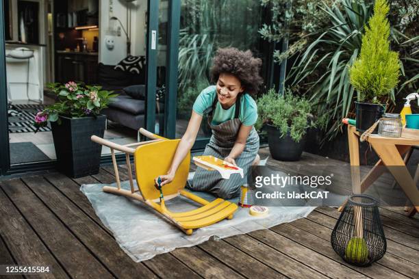 la mujer está coloreando una silla en casa - handy fotografías e imágenes de stock