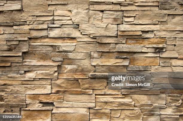 beige sandstone tiles on a surrounding wall - sandstone wall stockfoto's en -beelden