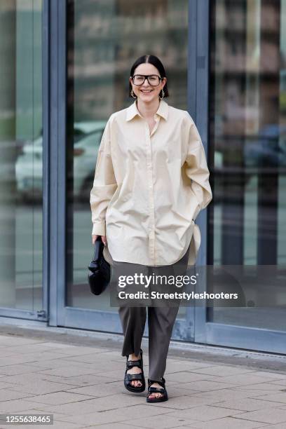 Influencer Maria Barteczko, wearing a light yellow oversized shirt by Arket, grey straight leg pants by Pixie Market, black chunky dad sandals by...