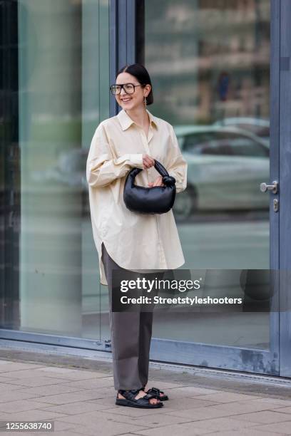 Influencer Maria Barteczko, wearing a light yellow oversized shirt by Arket, grey straight leg pants by Pixie Market, black chunky dad sandals by...