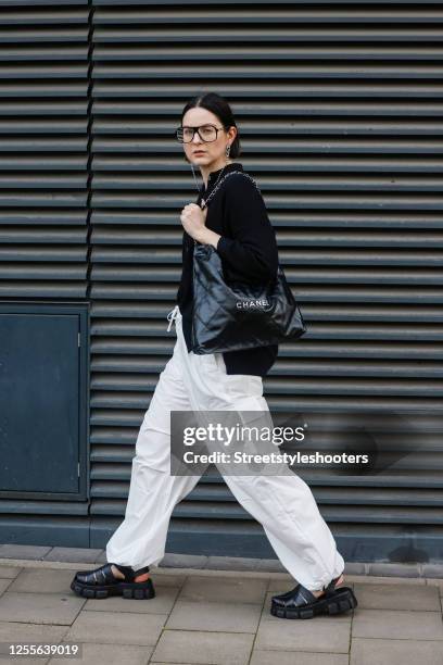 Influencer Maria Barteczko, wearing a black knitted polo shirt by Gitta Banko, white nylon cargo pants by Bershka, black gurkha fisherman sandals by...