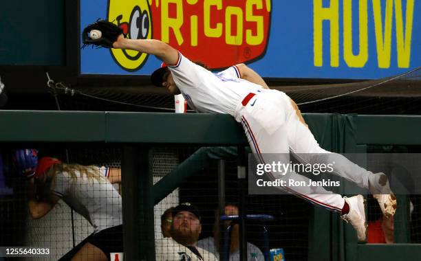 Josh Smith of the Texas Rangers goes over the rail to catch a fly ball hit by Eddie Rosario of the Atlanta Braves during the fourth inning at Globe...