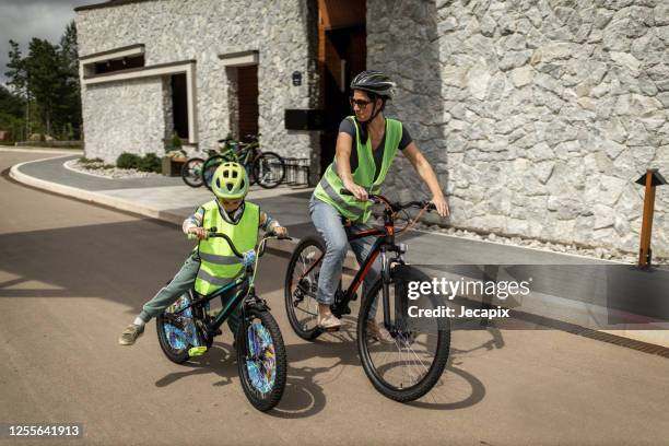 jonge moeder die fiets met haar zoon berijdt - reflecterende kleren stockfoto's en -beelden