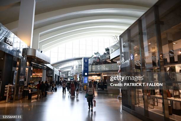 Travelers walk past retail stores and restaurants inside the Tom Bradley International Terminal at Los Angeles International Airport in Los Angeles,...