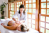 Massage therapist doing massage in a beautiful woman