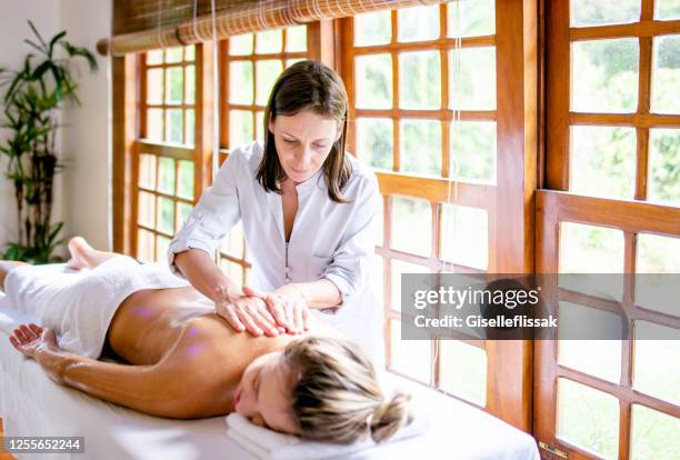 massage therapist doing massage in a beautiful woman - masseuse stock pictures, royalty-free photos & images