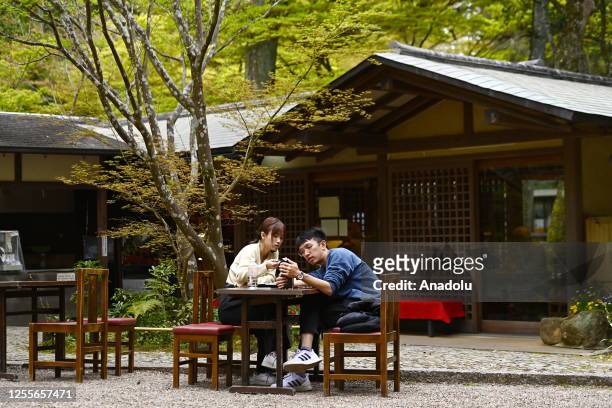 Young tourist couple relax at a traditional Japanese teahouse in Nara Park along a path leading to Kasuga-taisha, the most important Shinto shrine in...
