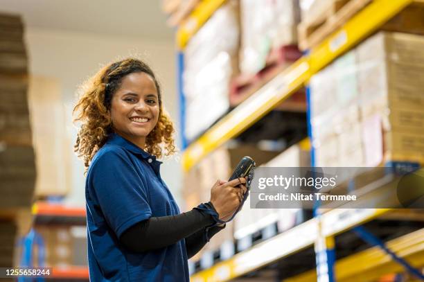 portrait of young african female employee using barcode handheld reader at warehouse. - baumarkt mitarbeiter stock-fotos und bilder