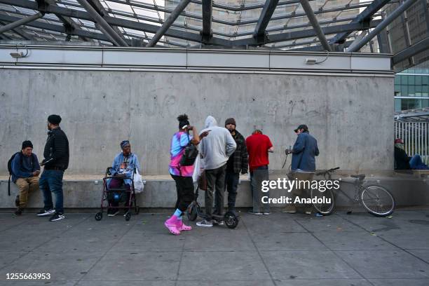 Homeless people stand on the street as homelessness rates rise due to the displacement of communities and citizens residing in low-income regions of...