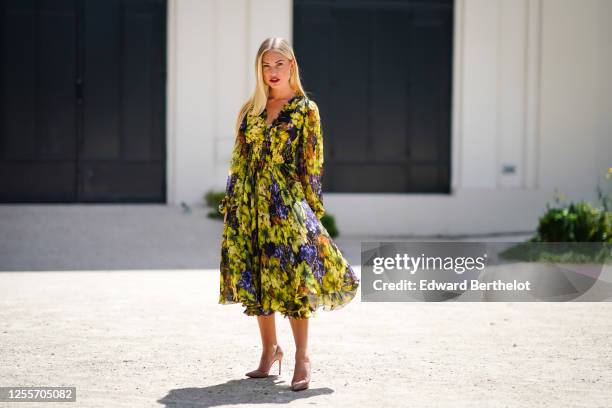 Lexi Fargo wears a green and purple long flowing ruffled dress with printed grapes and leaves from Dolce & Gabbana, pink Louboutin pointy high heeled...