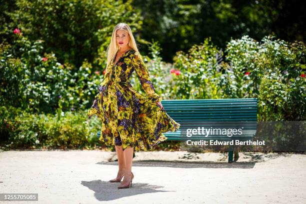 Lexi Fargo wears a green and purple long flowing ruffled dress with printed grapes and leaves from Dolce & Gabbana, pink Louboutin pointy high heeled...