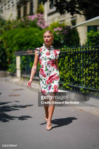 Lexi Fargo wears a white ruffled sleeveless short dress with green and red floral print from Dolce & Gabbana, Louboutin beige pointy shoes, earrings...