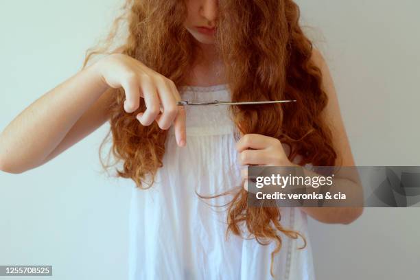 teenage girl cutting her long, curly hair - cutting long hair stock pictures, royalty-free photos & images