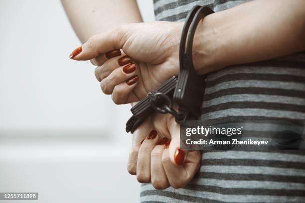 hands in handcuffs behind the back of arrested woman - woman prison stock-fotos und bilder