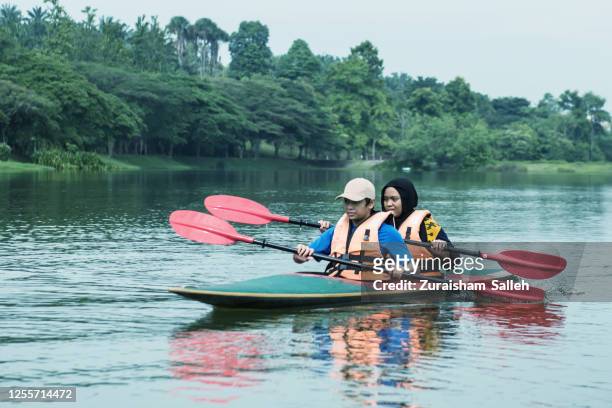 junge asiatische junge und mädchen erkunden see auf kajak - k1 kayaking stock-fotos und bilder