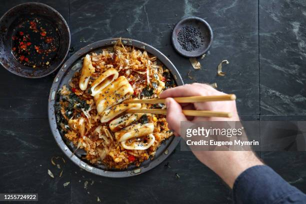 adult man eating japanese grilled squid with teriyaki sauce on topped fried rice bowl - chinese takeout stock pictures, royalty-free photos & images