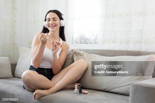 woman applying nail polish on sofa - nail file stock pictures, royalty-free photos & images