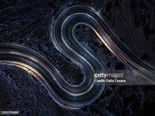 aerial view of a winding road at night time. cars light trails on an s-shaped rural road. - wegen stockfoto's en -beelden