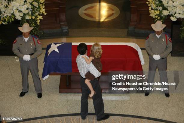 Man holds a young girls while looking at the casket of former Texas State Governor Ann Richards during the public visitation in the rotunda at the...