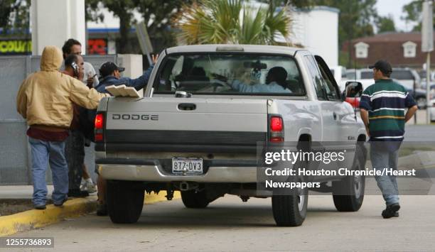 Migrant workers surround a vehicle while waiting for contruction work in front of a Home Depot store in Kenner, Louisiana October 20,2006. James...