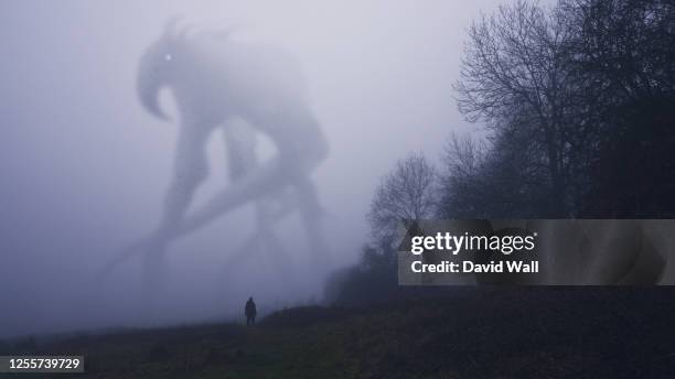 a huge monster appearing out the fog on a winters day. with a lone figure looking up. - monstre photos et images de collection