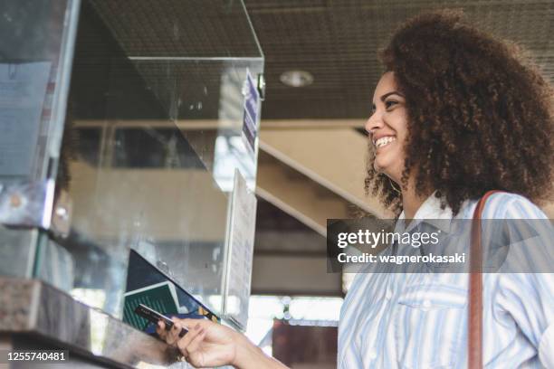 jeune femme achetant des billets à une billetterie - hygiaphone photos et images de collection