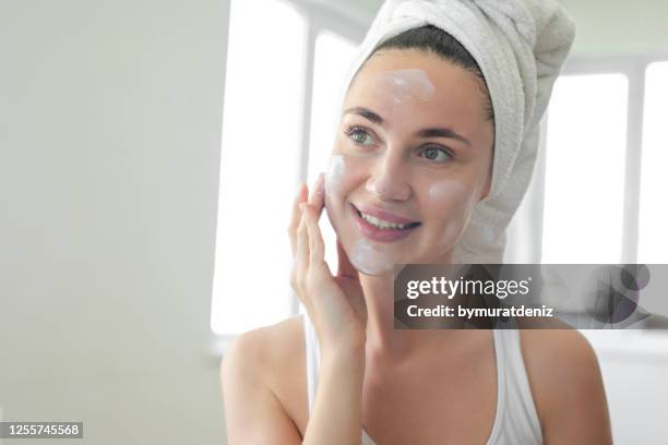 woman putting face cream on her face - putting lotion stock pictures, royalty-free photos & images