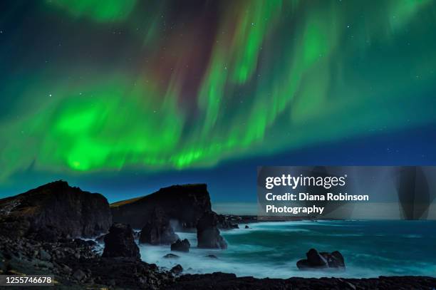 stars and aurora borealis streaming over sea stacks, waves and rocky shoreline of the greenland sea on the reykjanes peninsula, iceland - iceland aurora stock pictures, royalty-free photos & images