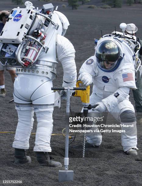 Space suit engineers Dustin Gohmert waits as Brian Daniel drills a hole while gathering rocks and soil samples while testing concept lunar space...