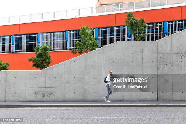slimme toevallige en jonge mens die in het bedrijfsdistrict loopt - street wall stockfoto's en -beelden
